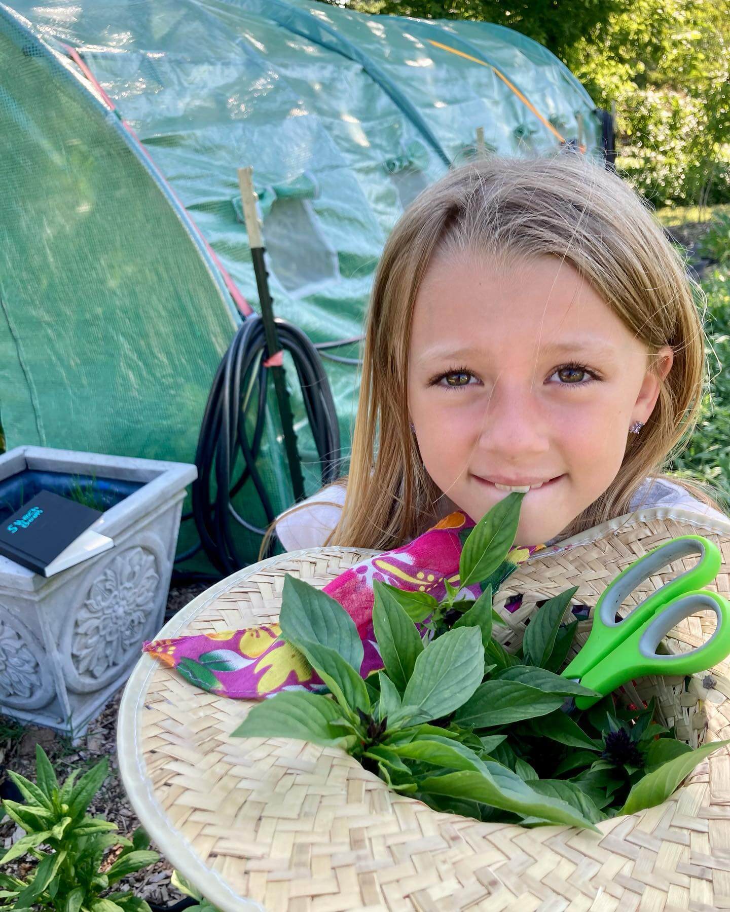 Little girl with straw hat full of herbs at Sassafras Hill homestead