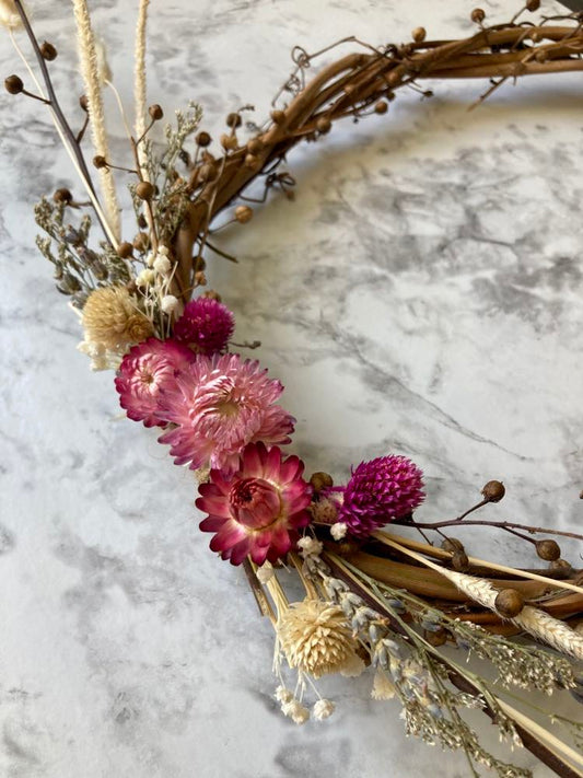 Close up of Small handcrafted wreath with dried grasses, vines and flowers by Sassafras Hill